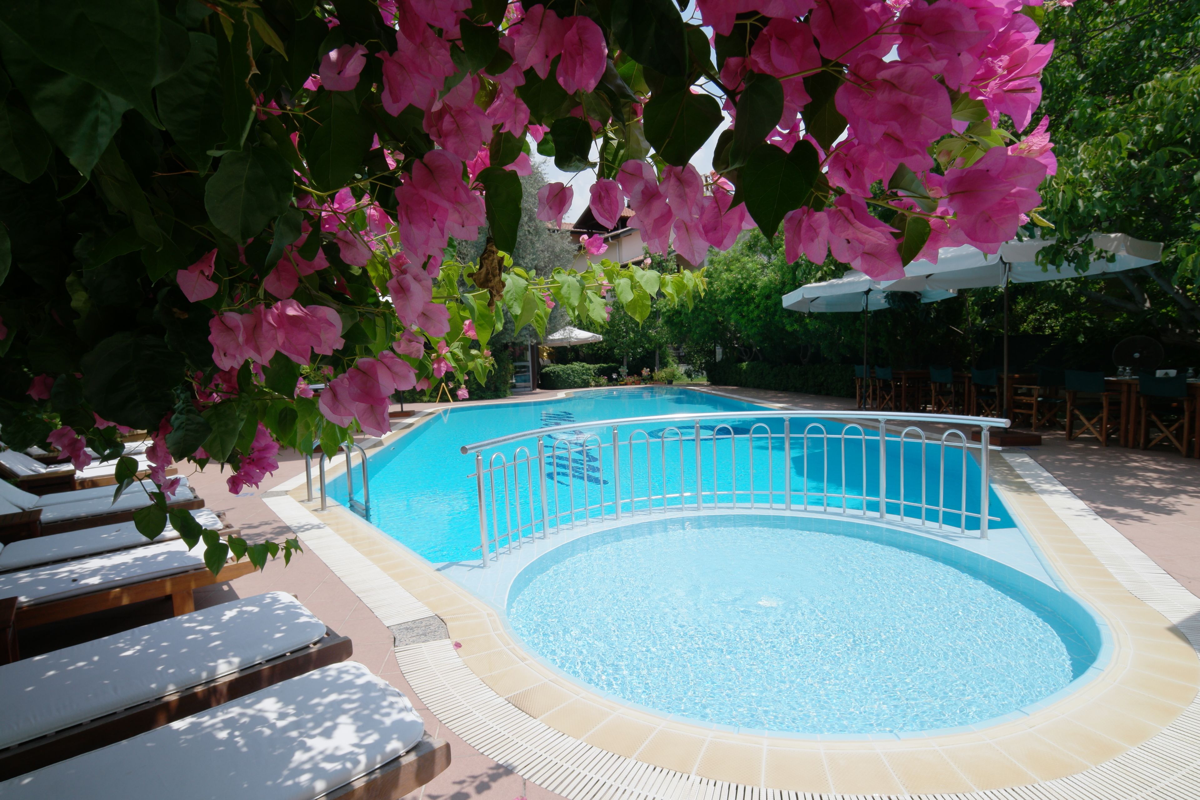 Una piscina con cubierta blanca, rodeada de sillas de descanso y sombrillas.