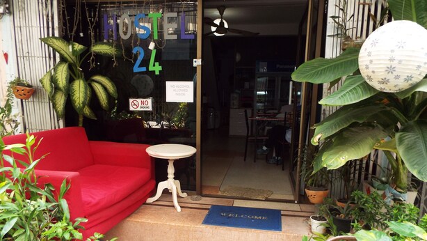 A hostel entrance with a red sofa, a small table, and various potted plants.