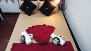 A neatly arranged massage area with a red towel, two rolled towels, and a white towel with a flower decoration.