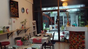 A dining area with tables set for four, a ceiling fan, and a view of the outside through a glass door.