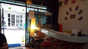 A hotel reception area with a counter, stools, and a view of the street outside.