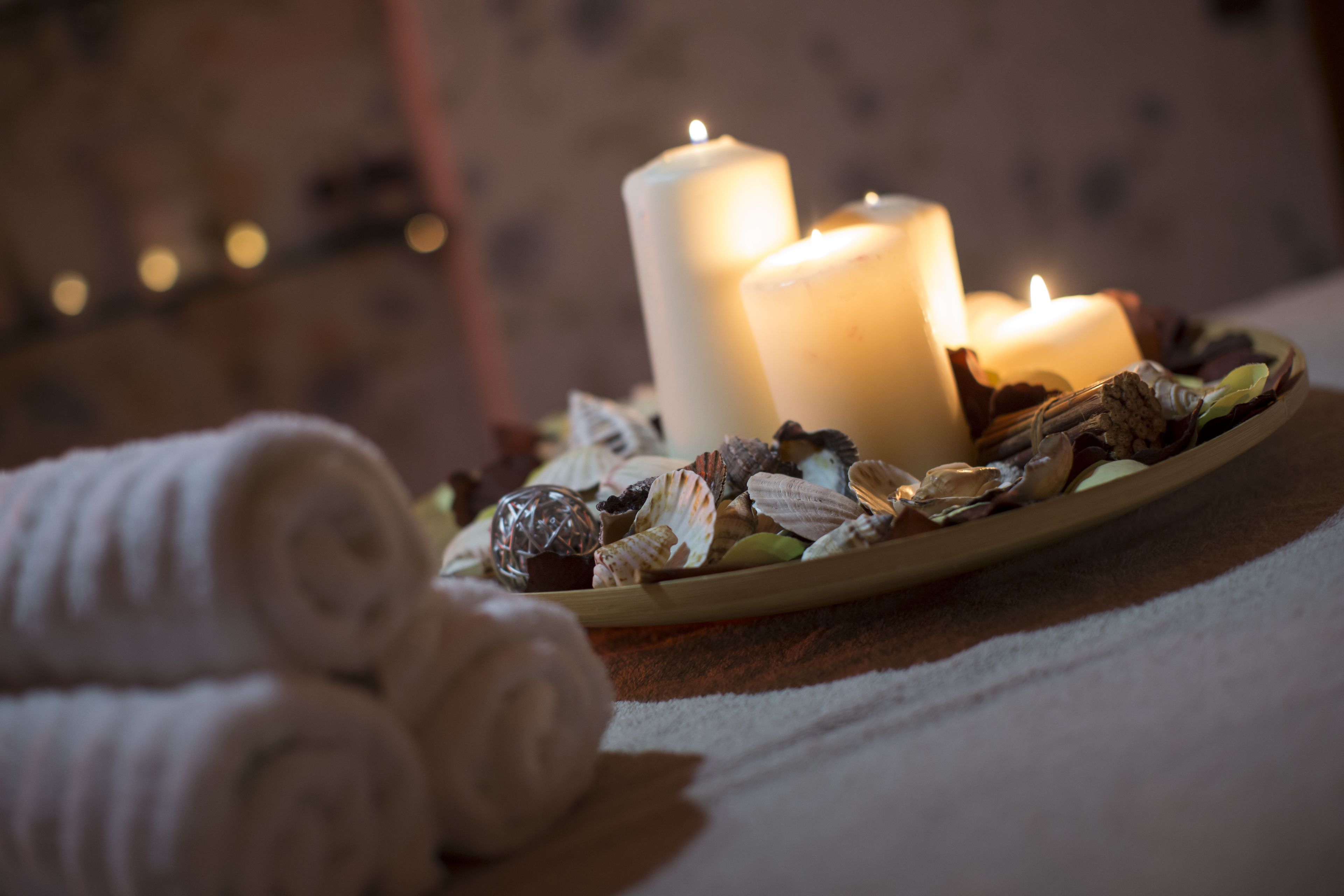 Een dienblad met kaarsen en gedroogde bloemen, wat een spa of ontspanningsomgeving doet vermoeden.