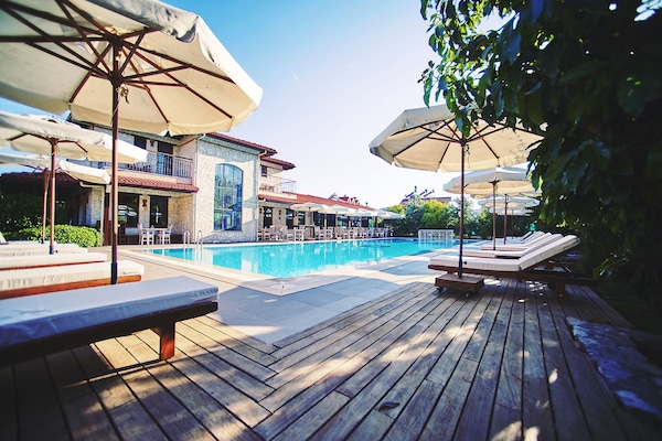 Una piscina techada, una piscina al aire libre, sombrillas