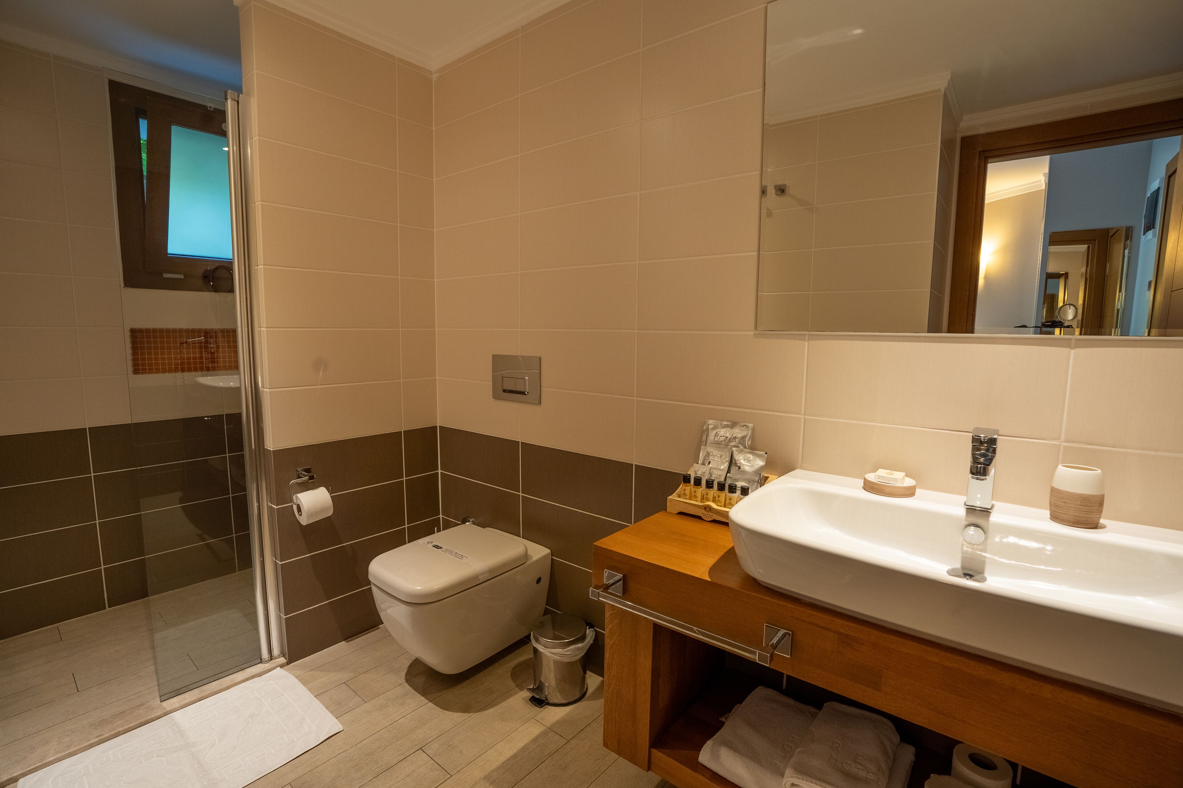 A bathroom with a shower, toilet, sink, and mirror.