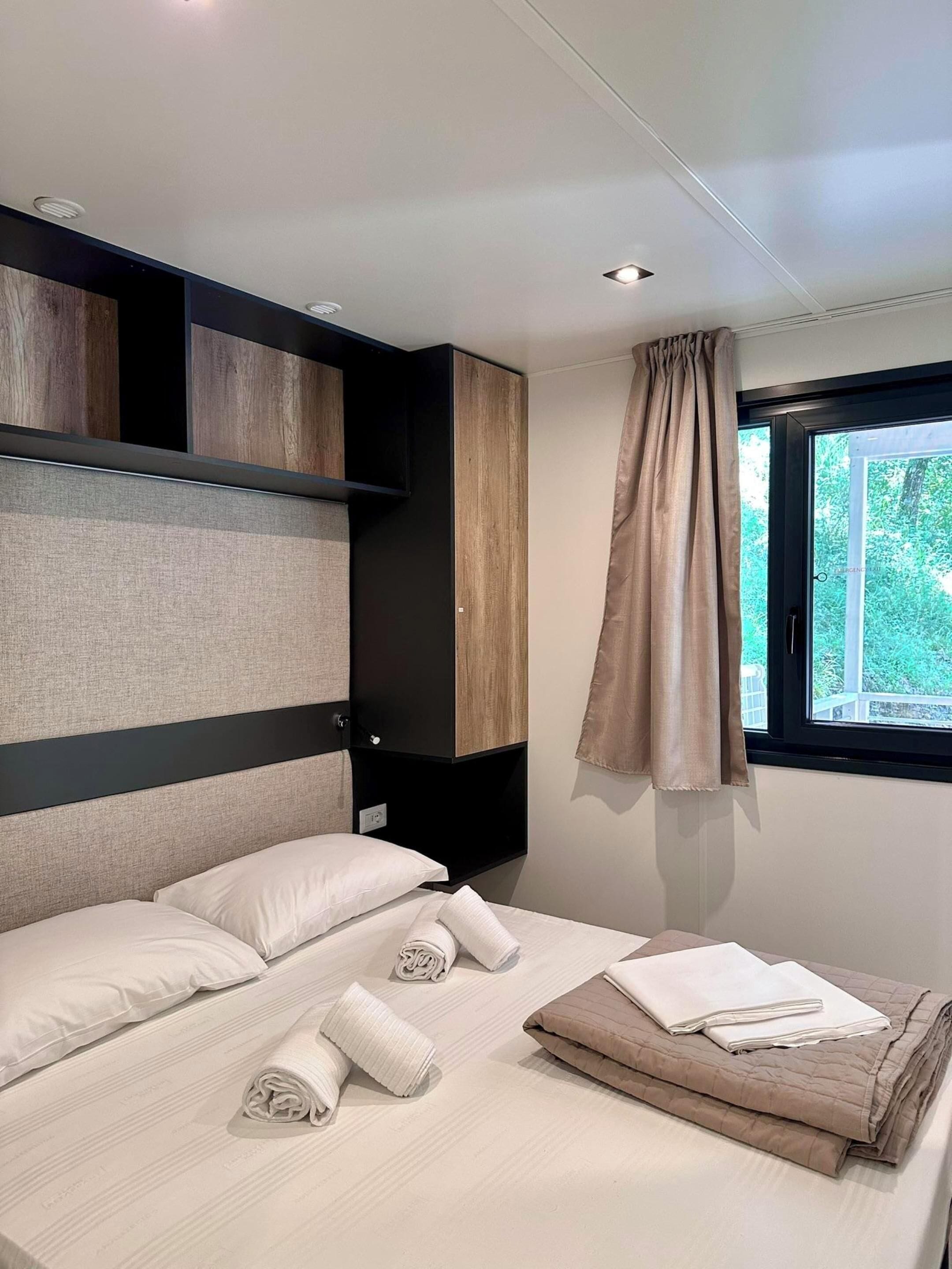 Una camera da letto moderna con un letto, cuscini e asciugamani piegati con cura.