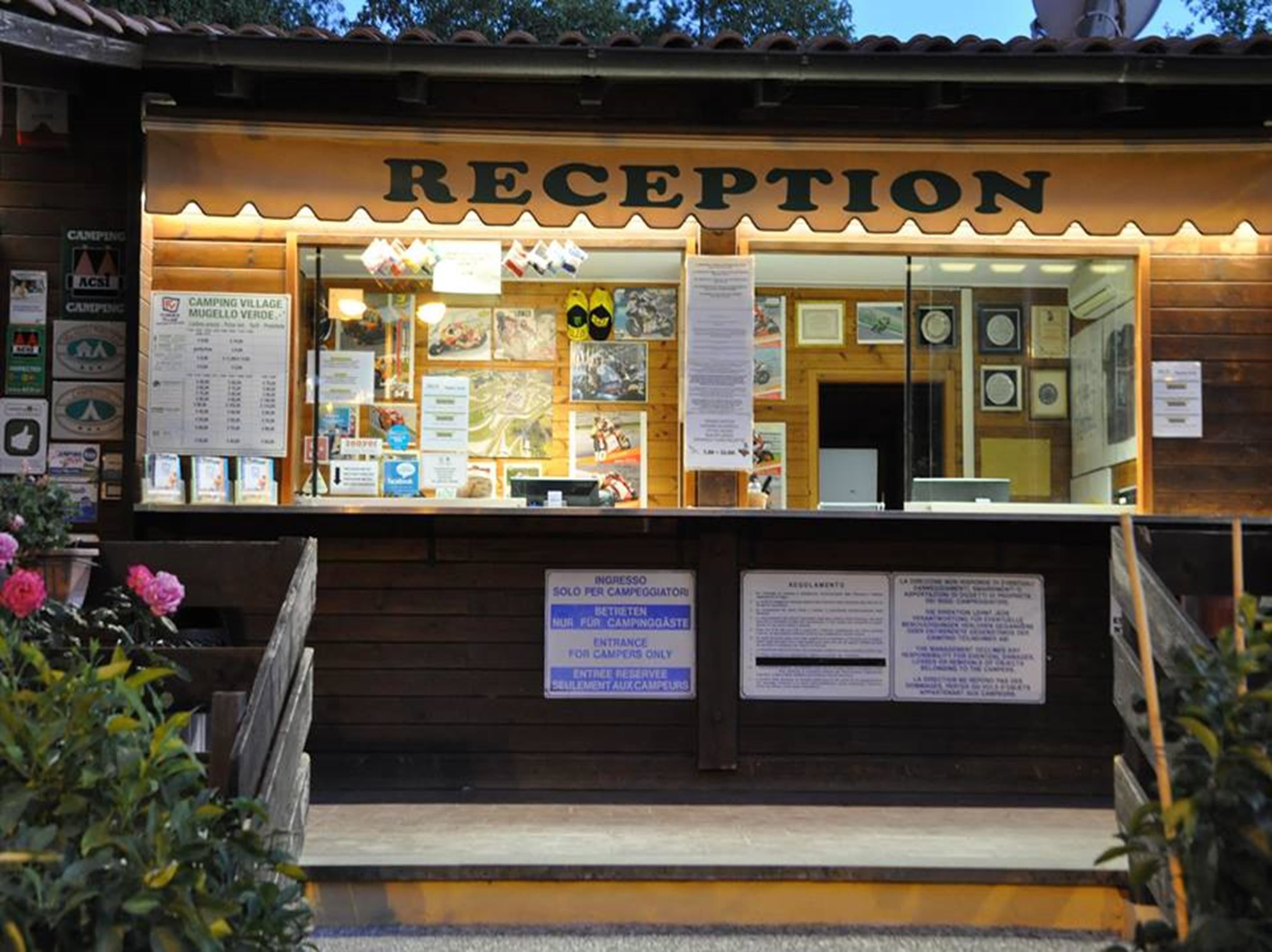 Ein Empfangsbereich mit Holzfassade, einem Schild mit der Aufschrift 'RECEPTION' und verschiedenen Informationspostern.