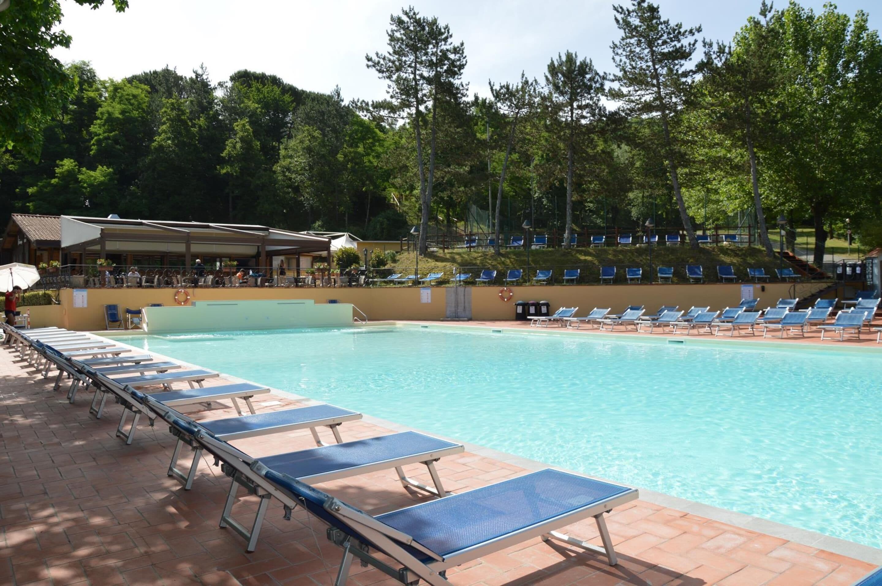 Une piscine avec des chaises longues et un espace abrité.