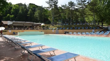 Une piscine avec des chaises longues et un espace abrité.