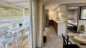 Une cuisine compacte équipée d’une cuisinière à gaz, d’un réfrigérateur et d’un petit coin repas avec une table et des chaises.
