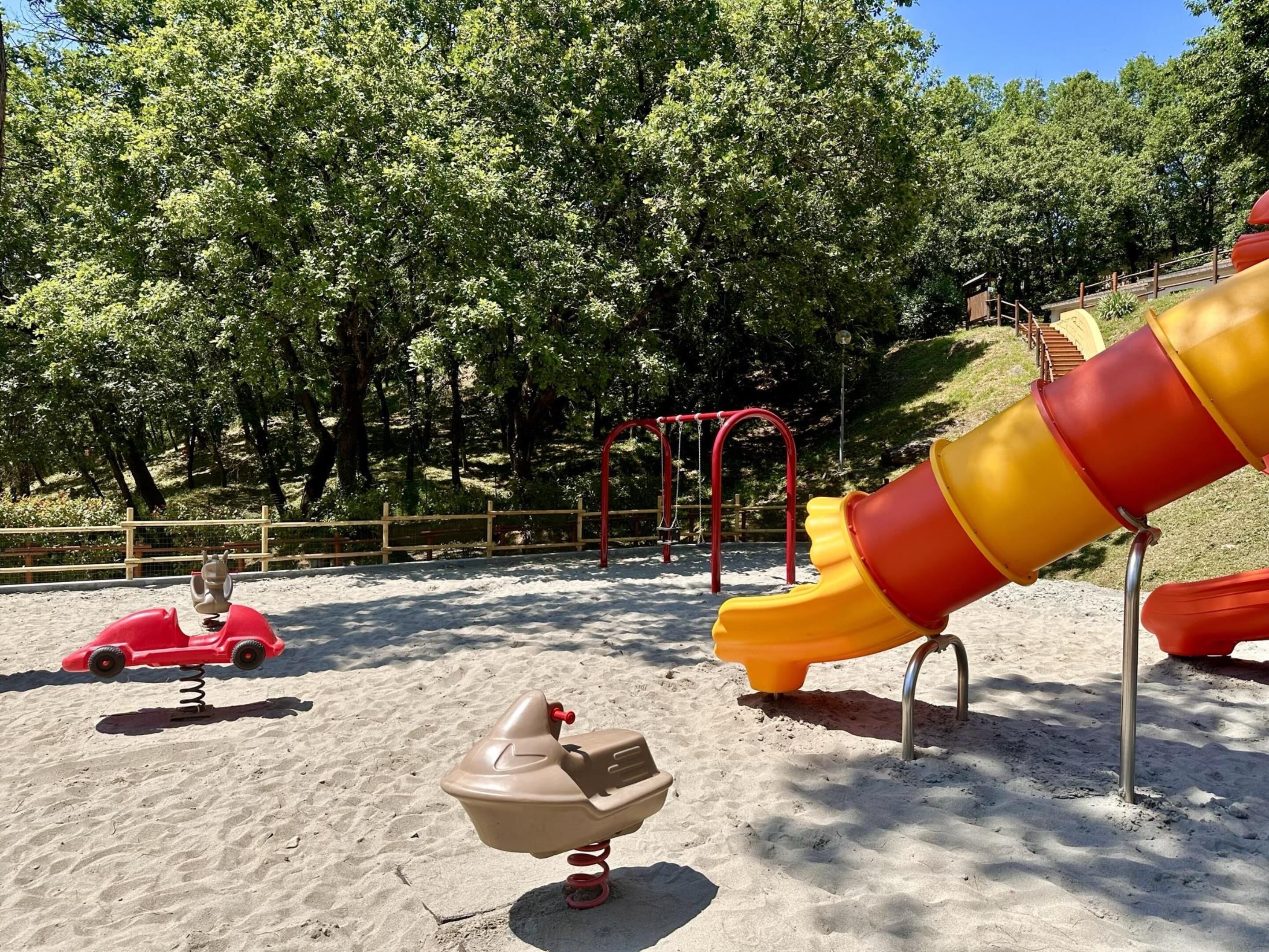 A playground with a slide, swings, and a sand play area.