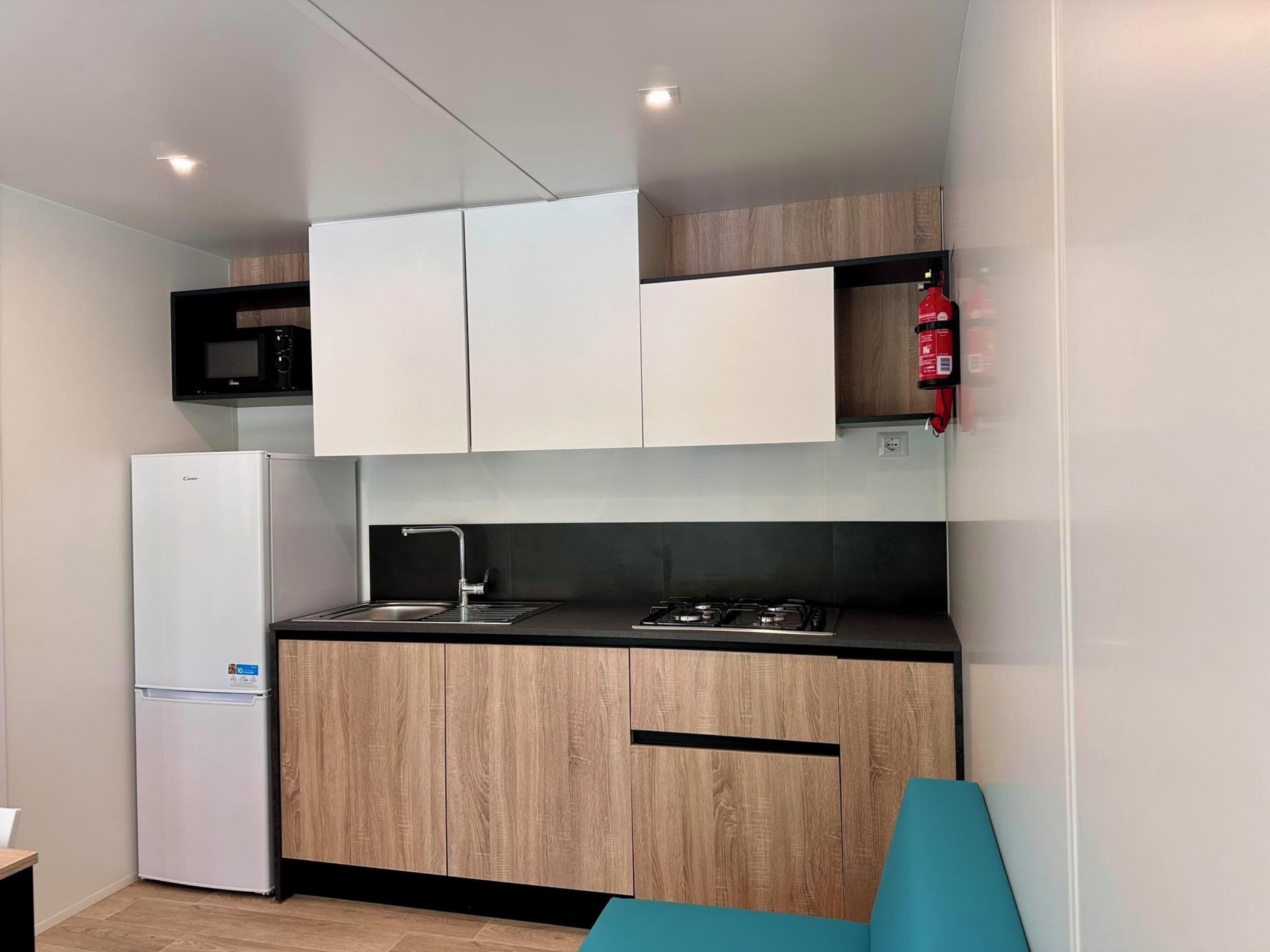 A compact kitchen with a refrigerator, microwave, sink, and stove.
