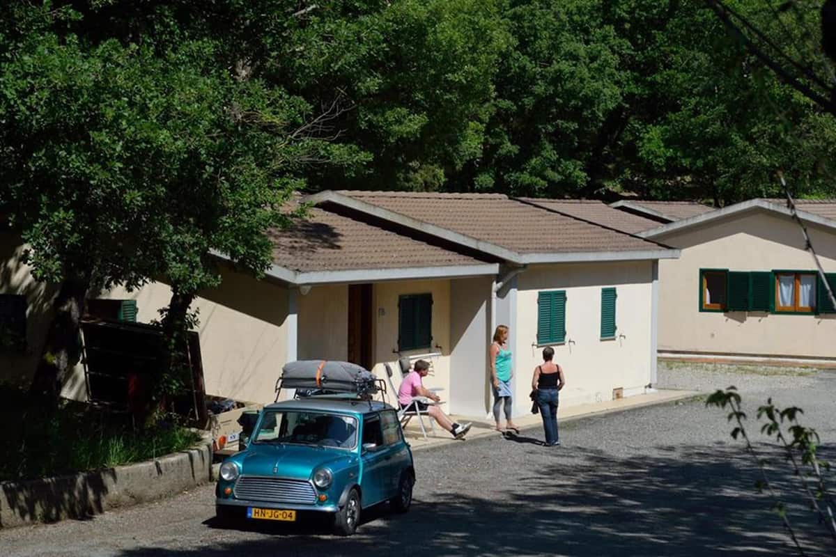 Un edifici petit amb una sola entrada i un cotxe estacionat al davant.