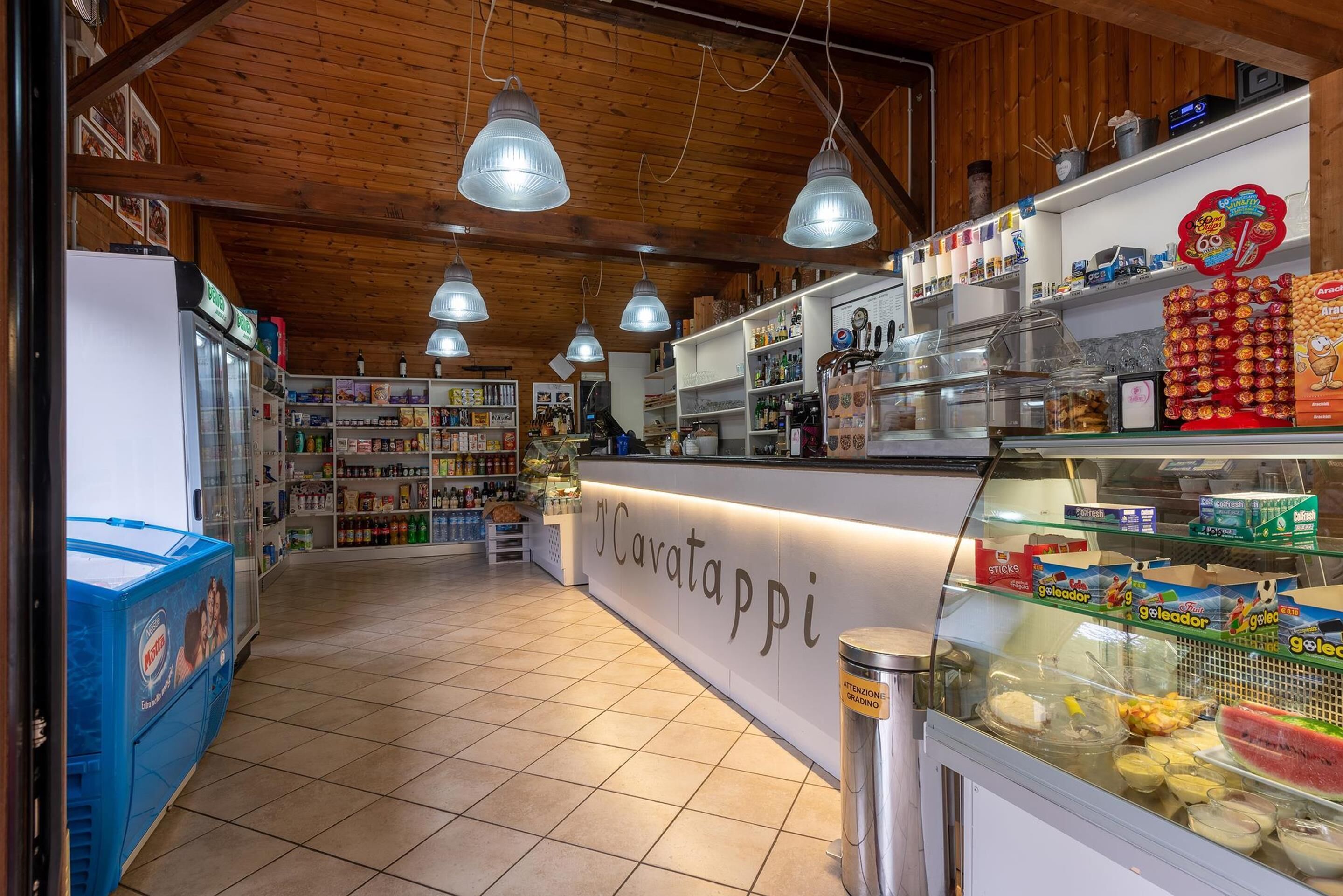 L’intérieur d’une boulangerie, avec un comptoir, des étagères remplies de produits de boulangerie et un présentoir réfrigéré.