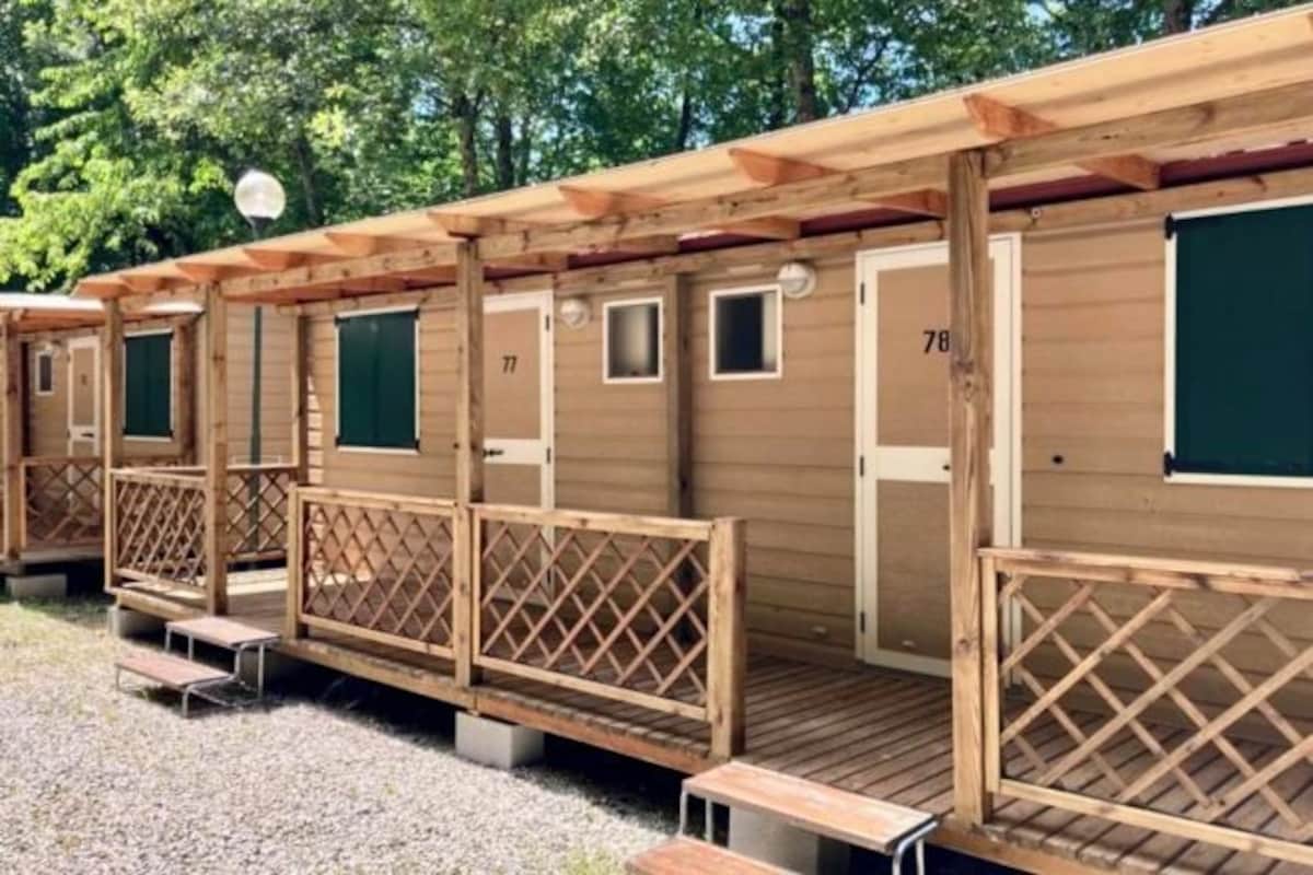 Een rij houten hutten met genummerde deuren, elk met een klein raam en een deur.
