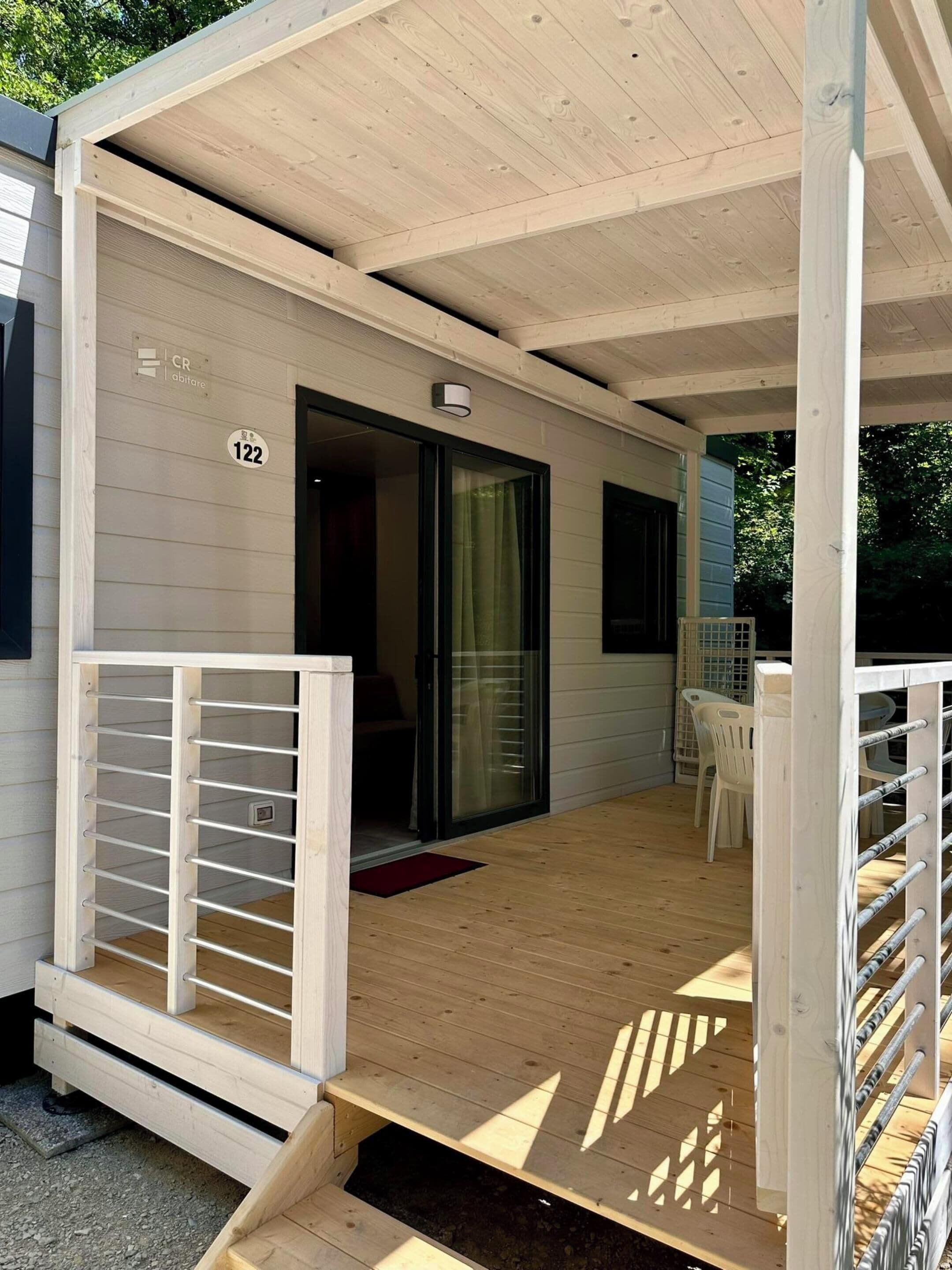 A wooden deck with a covered area, a sliding glass door, and a small table with chairs.