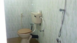 A small bathroom with a toilet, a shower, and tiled walls. - Natural Cabanas (Tangalle)