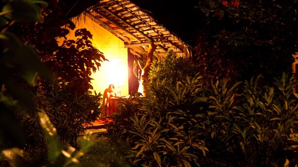A small, illuminated structure surrounded by dense foliage at night. - Natural Cabanas (Tangalle)