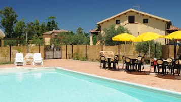 Una piscina al aire libre de temporada, sombrillas, tumbonas