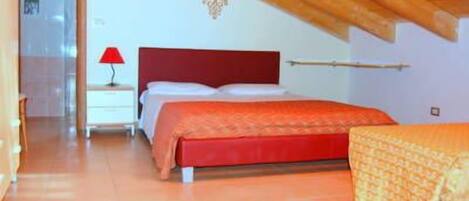 Un dormitorio con una cama, una mesita de noche, una lámpara y un cabecero rojo.