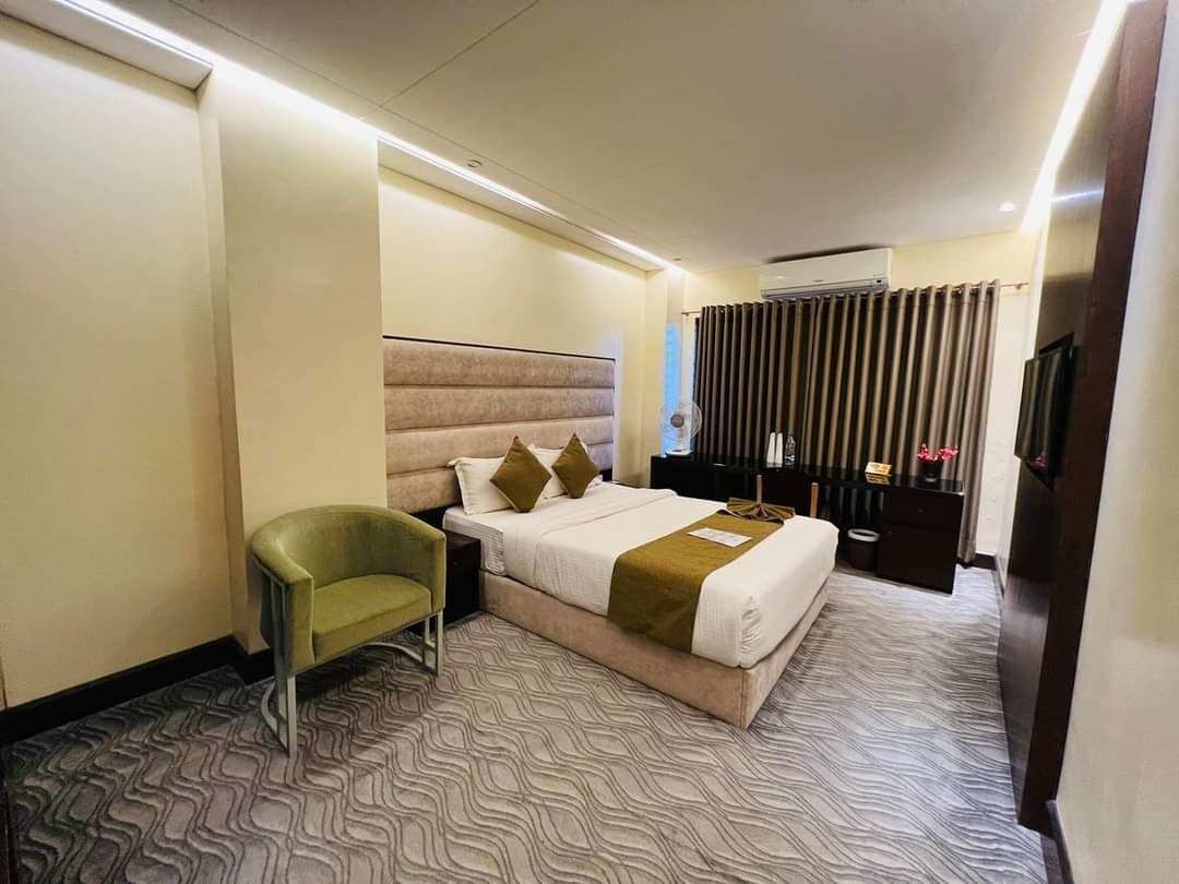 A hotel room with a bed, a chair, a desk, and a television.