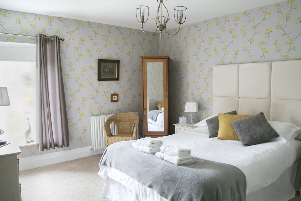 A bedroom with a large bed, a mirror, a dresser, and a chair.