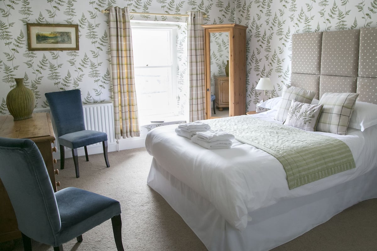 A bedroom with a bed, a chair, a dresser, and a mirror.
