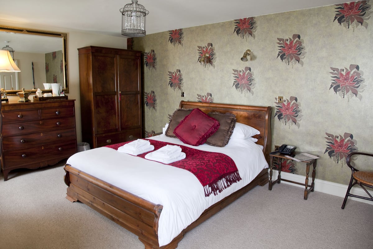 A bedroom with a wooden bed, a dresser, a nightstand, and a chair.