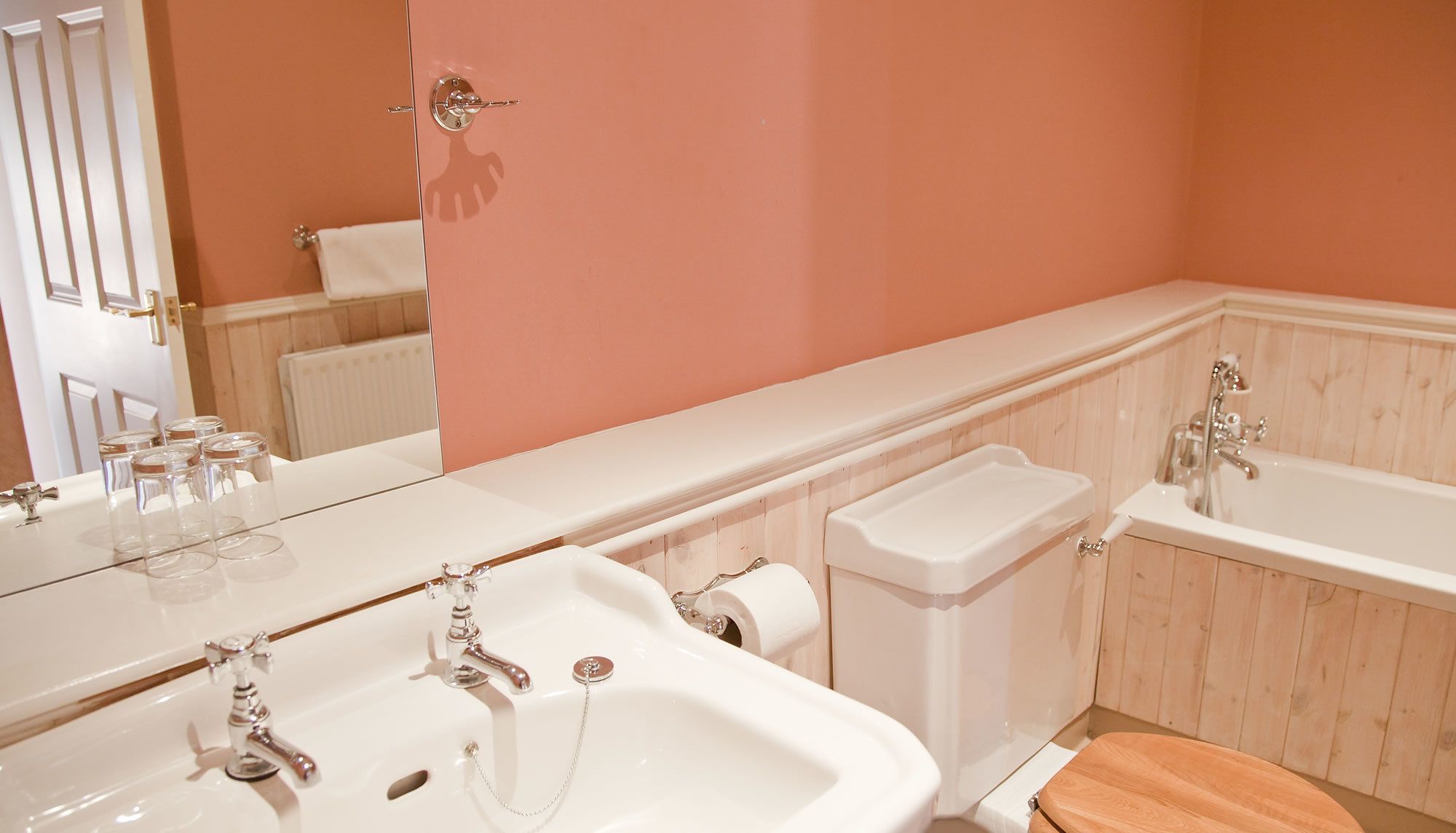 Un baño con un espejo grande, dos lavamanos, una bañera y un inodoro.
