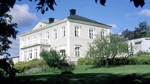 A large, two-story building with a symmetrical facade, multiple windows, and a well-maintained lawn. - Söråkers Herrgård (Soraker)