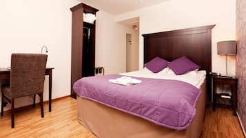 A hotel room with a bed, a desk, a chair, and a nightstand.