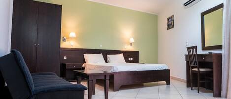 Habitación de hotel con cama, escritorio, silla, sofá y dos lámparas de pared.