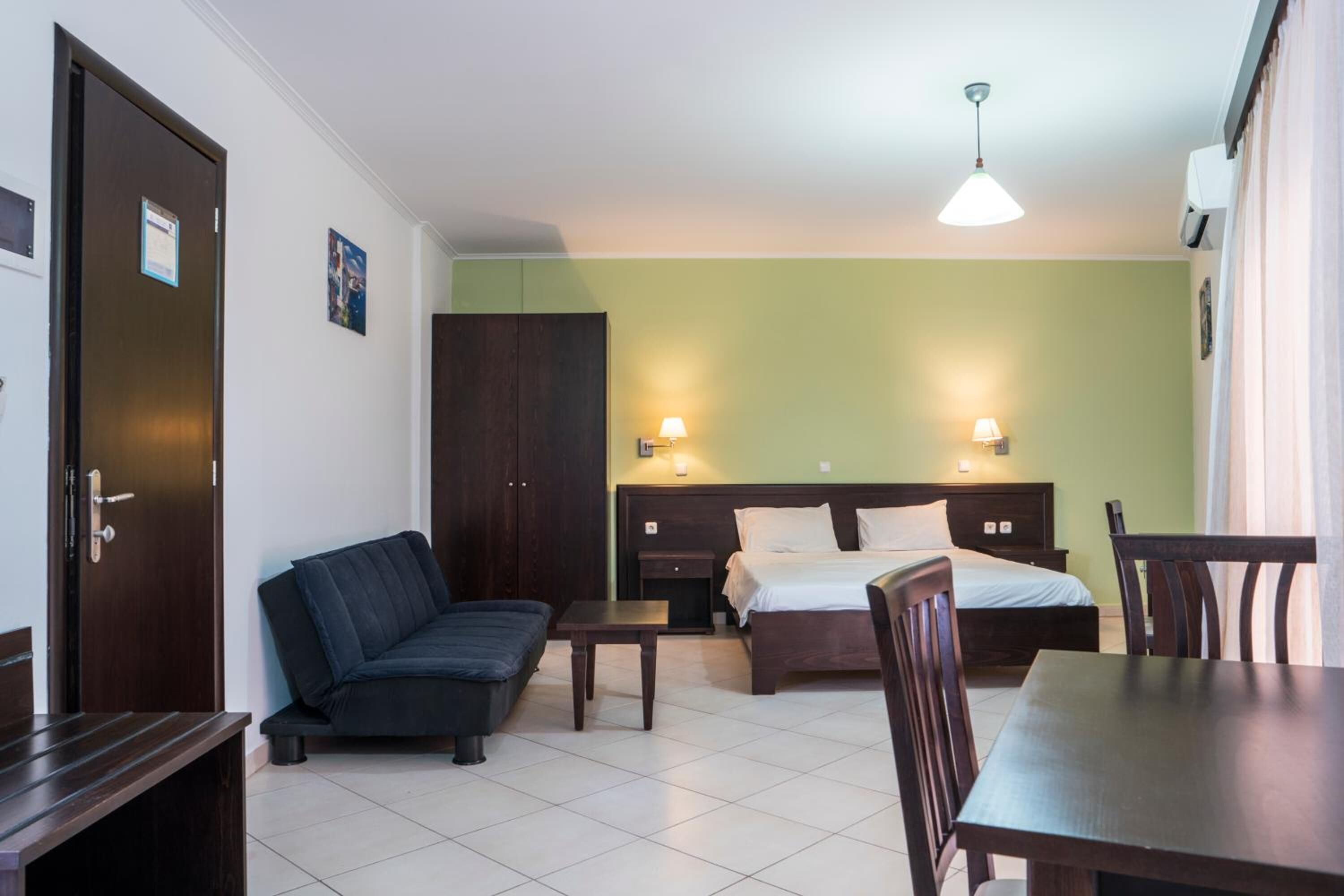 Una habitación de hotel con una cama, un sofá, una mesita y una mesa de comedor.