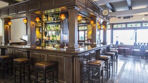 A bar area with wooden bar stools, a well-stocked liquor shelf, and a clock on the wall. - Rio Hotel (Kos)