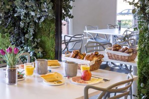 A breakfast setting with a table set for two, including croissants, bread, fruit, and juice. - Sure Hotel by Best Western Saint-Amand-Les-Eaux (Saint-Amand-les-Eaux)
