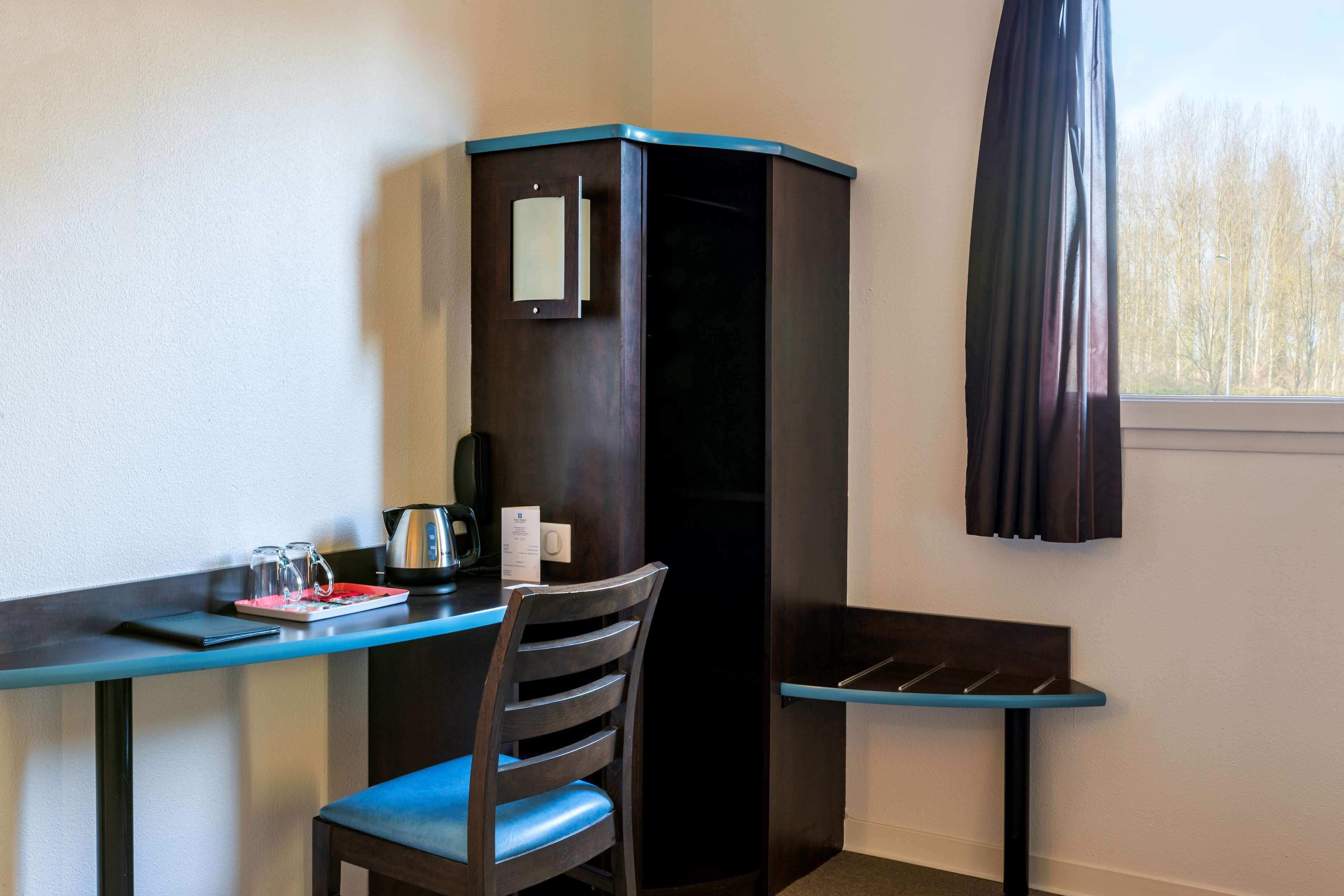 Habitación de esquina con escritorio, silla y armario.