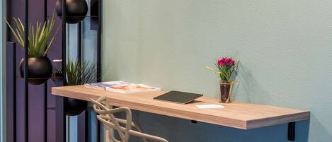 A modern workspace with a wooden desk, a chair, and potted plants.