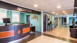 A reception area with a reception desk, a clock, and a wall-mounted decorative piece.