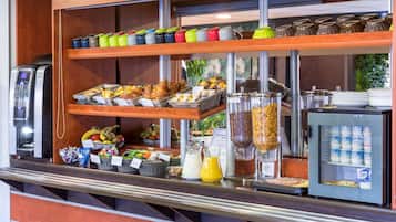A breakfast buffet with various food items, a coffee machine, and a refrigerator with dairy products.