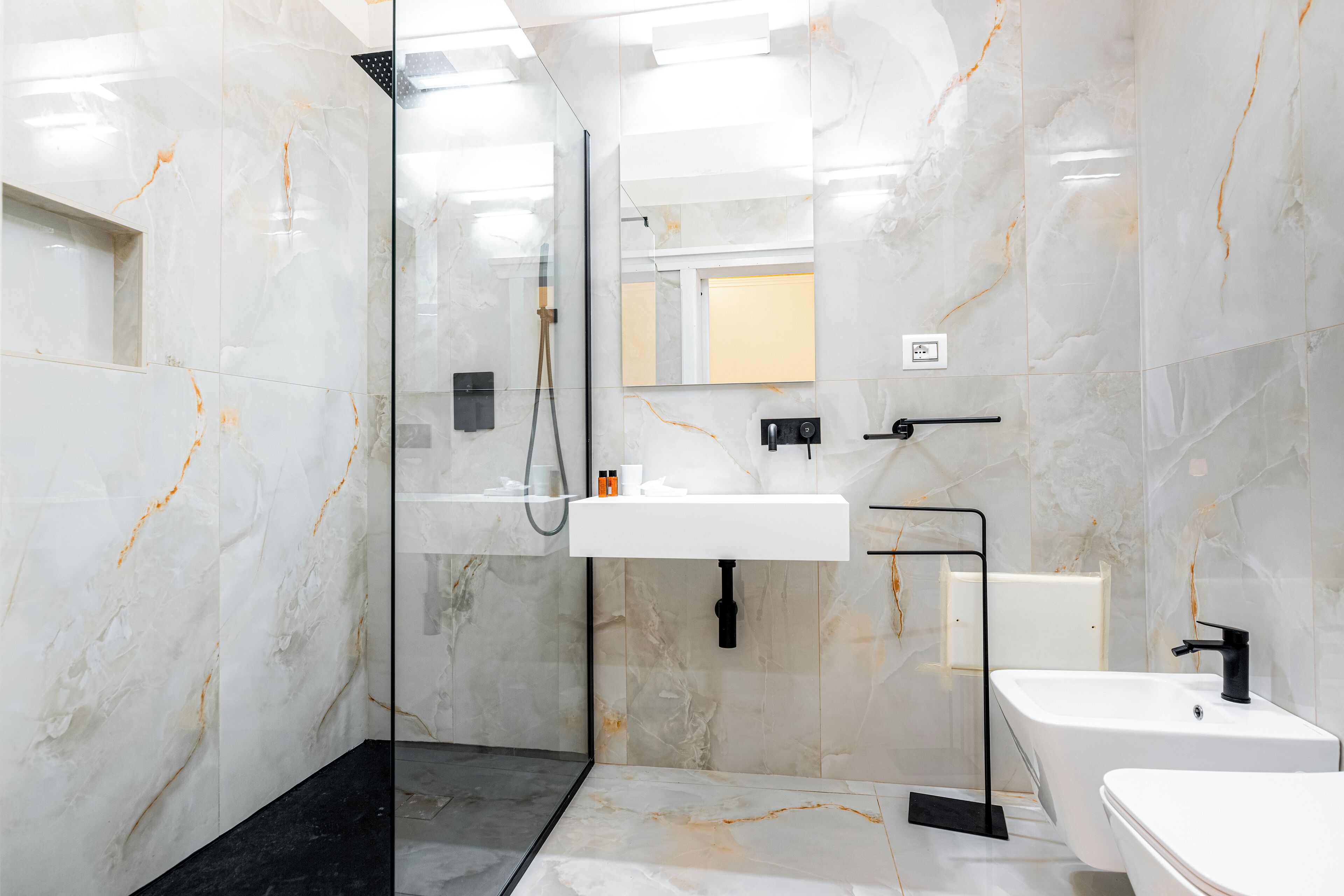 Een moderne badkamer met een douchecabine van glas, een wit wastafelmeubel en een zwart bad.