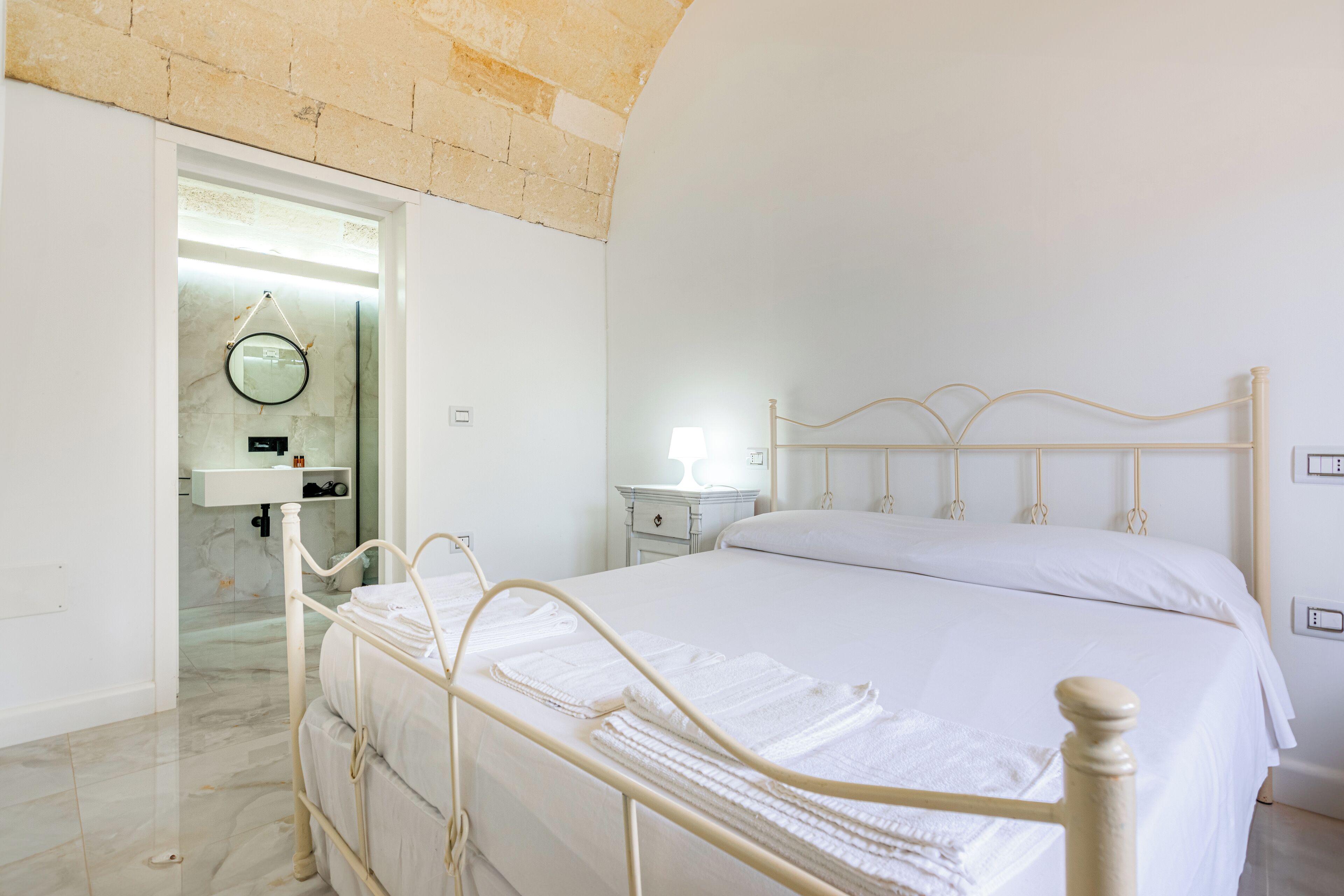 A spacious bedroom with a large bed, a bedside table, and a nightstand.