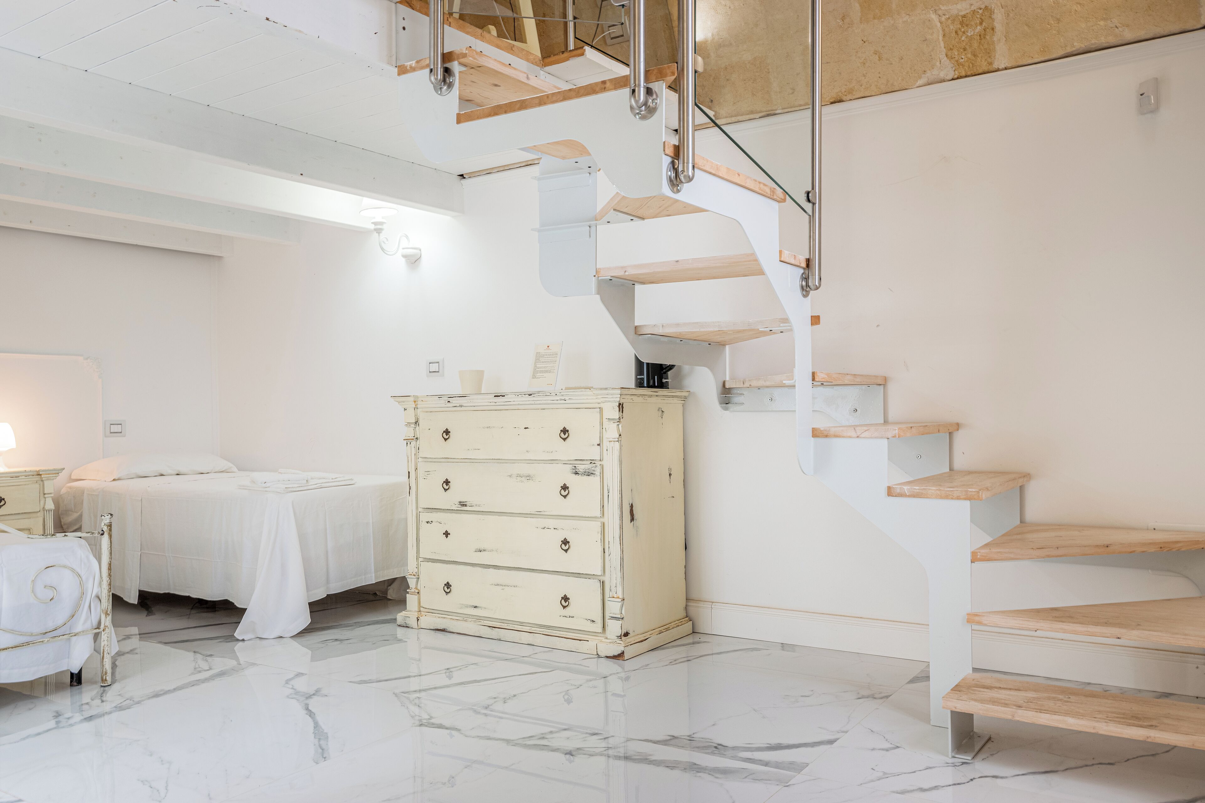 Un dormitorio con una cama, un aparador y una escalera.