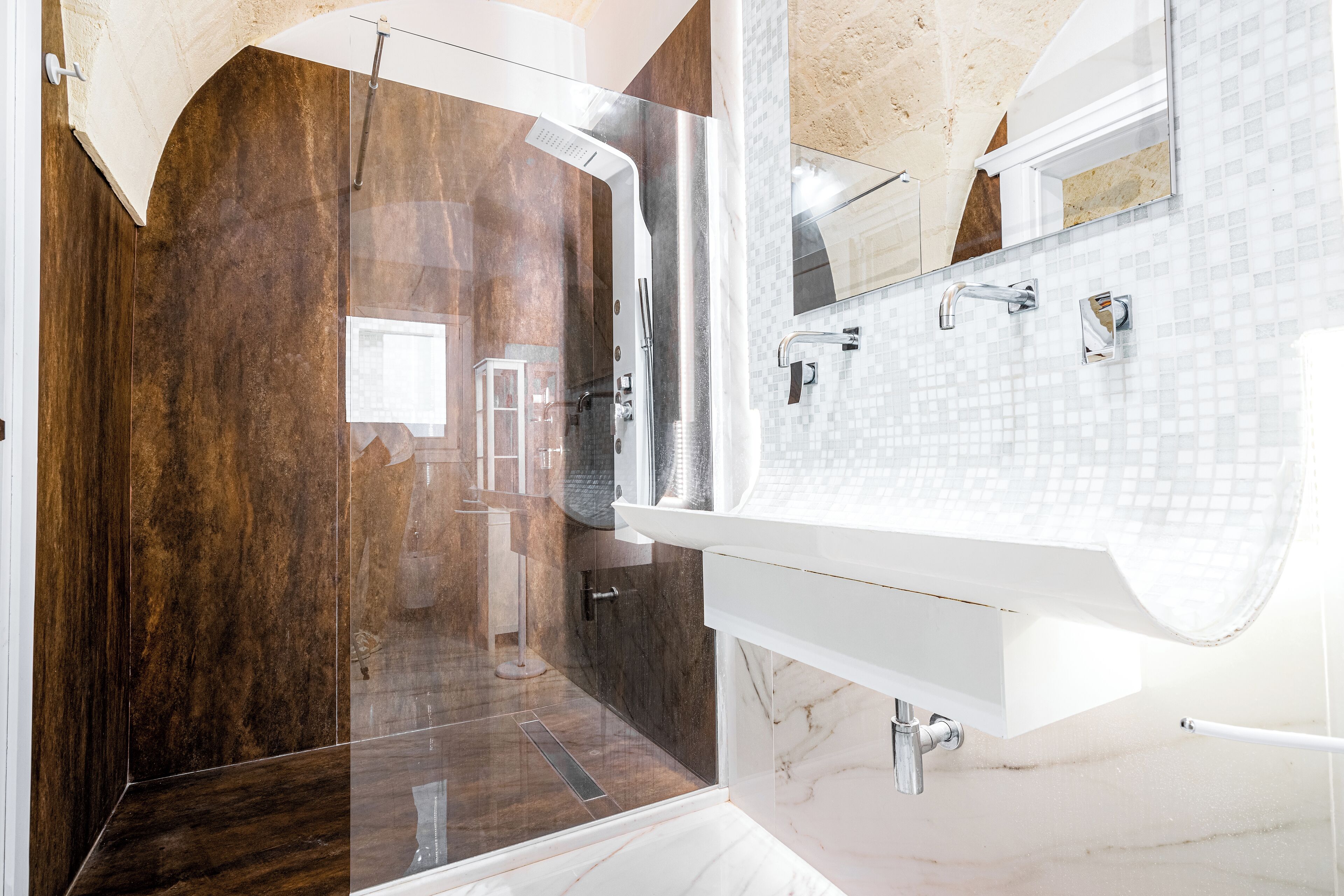 A modern bathroom with a glass-enclosed shower, a white sink, and a marble backsplash.