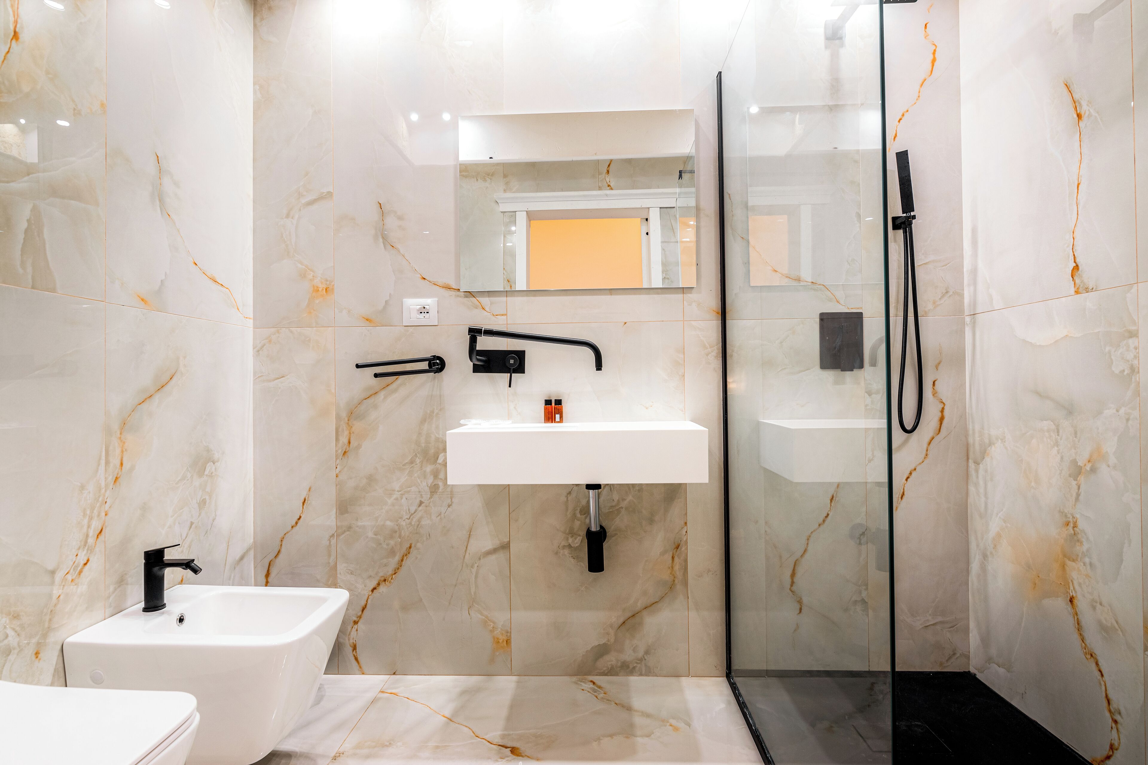 A modern bathroom with a white sink, black faucet, and a glass-enclosed shower area.