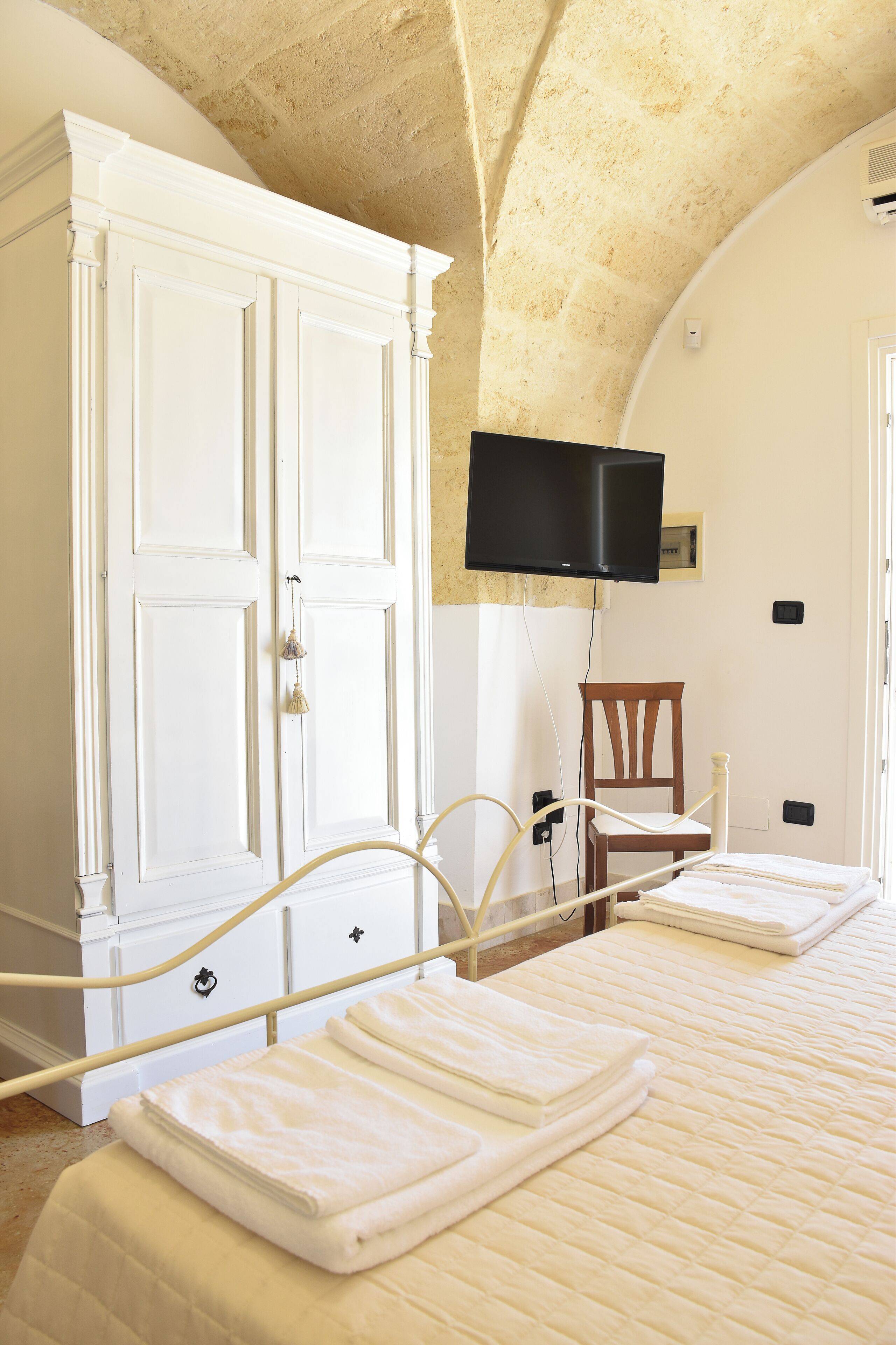 Une chambre à coucher comprenant un lit, une armoire, un téléviseur fixé au mur et une chaise.