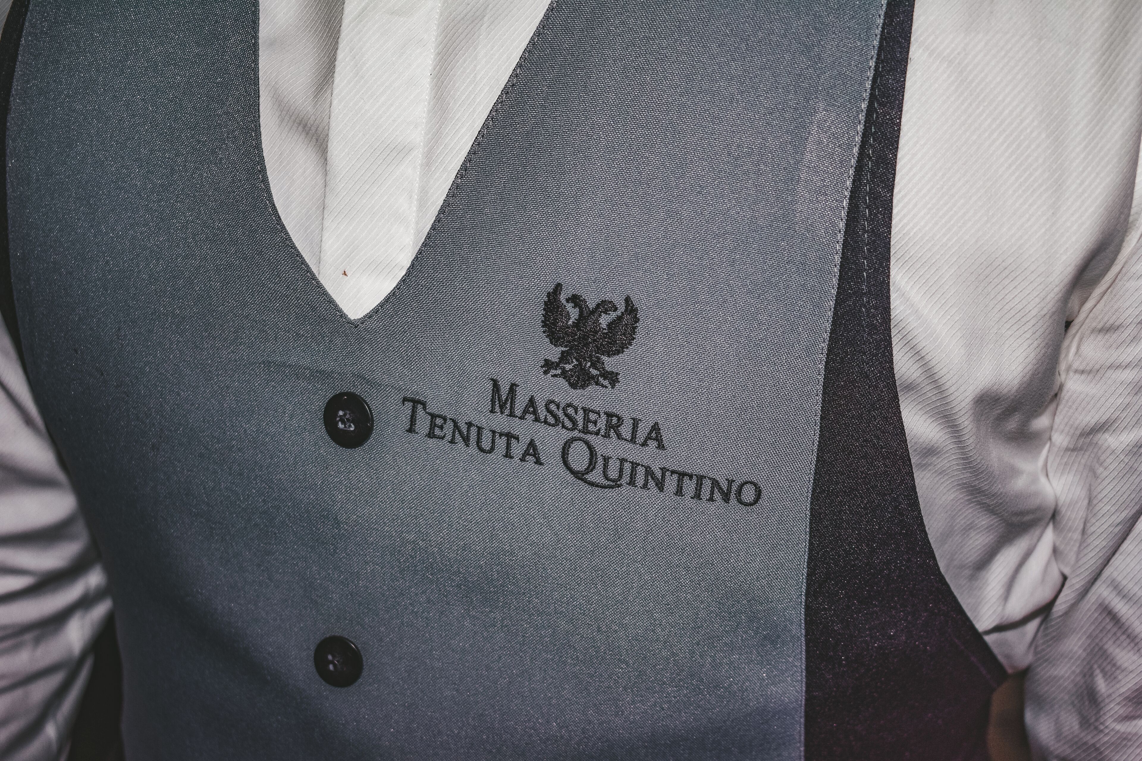 Un gilet orné du texte « MASSERIA TENUTA QUINTINO » et d’un emblème représentant un aigle.