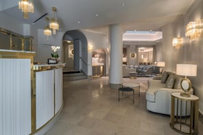 Een ruime hotellobby met een receptiebalie, een zithoek en een trap naar de andere verdiepingen.