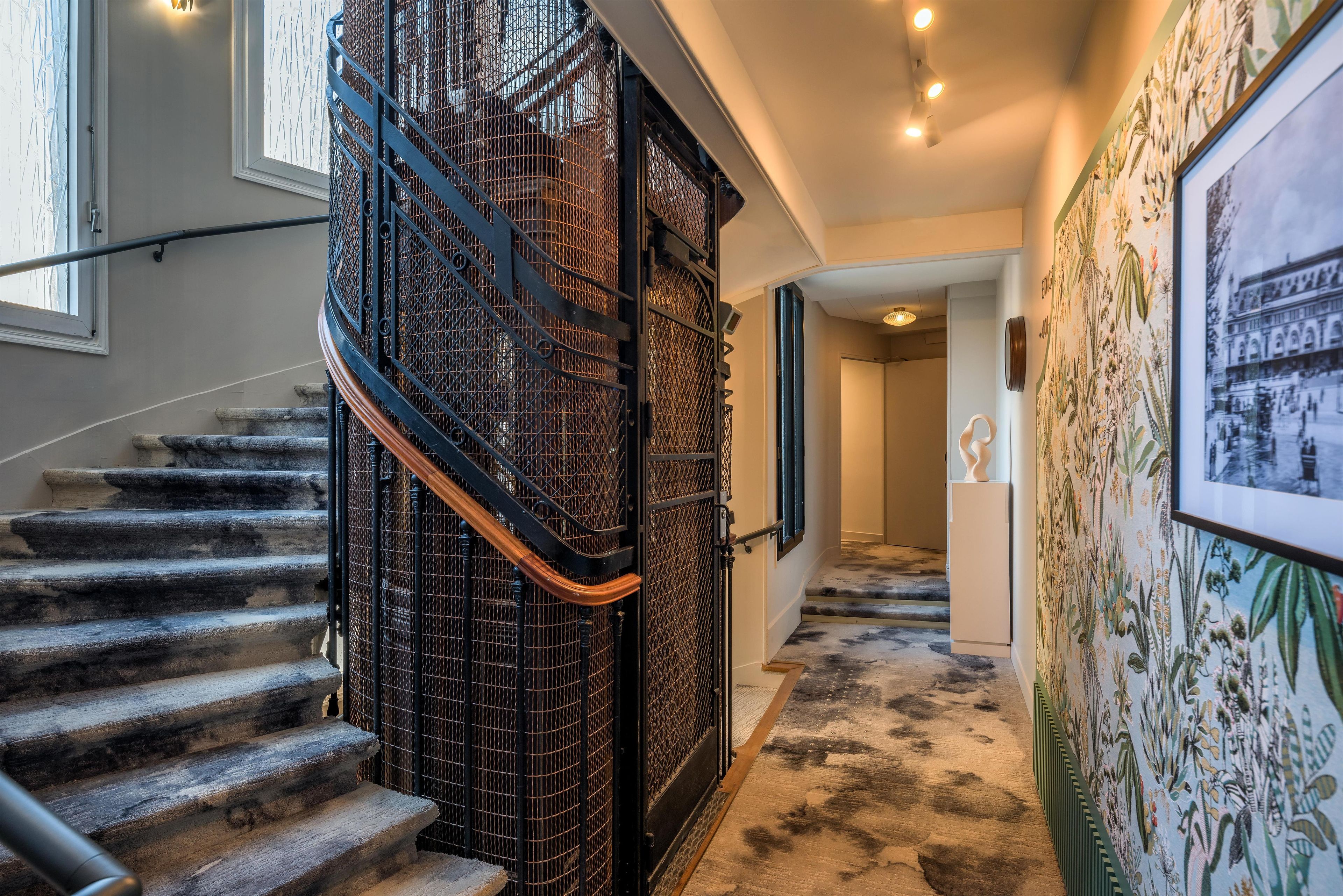 A staircase with a metal railing and a carpeted floor leading to a hallway with a wall-mounted picture.