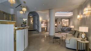 Un moderno vestíbulo de hotel con mostrador de recepción, zona de estar y una escalera que conduce a pisos superiores.