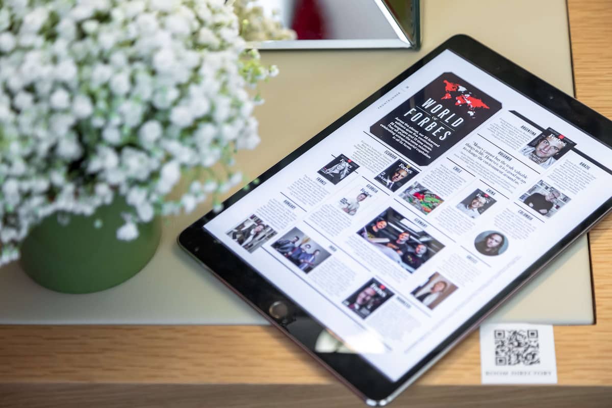 Una tableta mostrando la revista World Forbes sobre una superficie de madera.