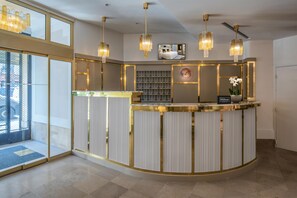 Un espace d’accueil d’hôtel avec un comptoir incurvé, un éclairage suspendu et un bureau de réception.